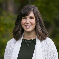 Creal Zearing head shot. Woman smiling with shoulder length brown hair. She is wearing a white sweater over a black shirt.