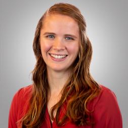 Erin Krysinski headshot. Woman smiling with long brown hair and wearing a red blouse.