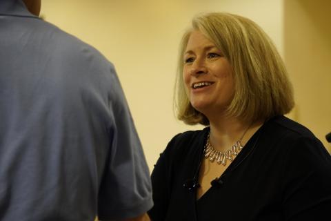 Woman with shoulder length blonde hair smiling and wearing a black shirt.