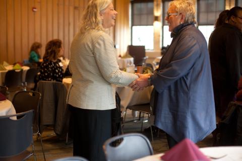 Two women greeting each other and shaking hands.