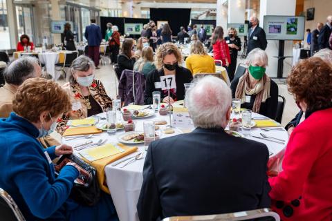 A group of people sitting at a formal table in a bright large space.