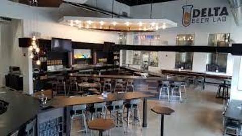 A brewery room with high top tables and bar taps in the background.