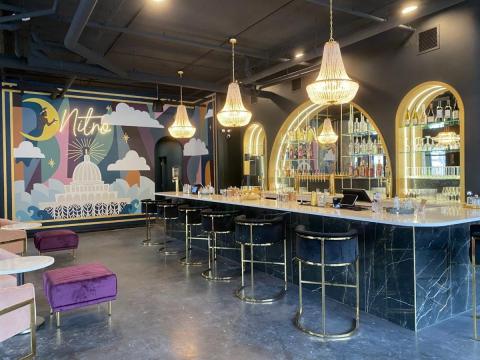 View of a room with a bar and brightly colored wall in the background. This is the inside of Nitro Lounge in Madison, WI.