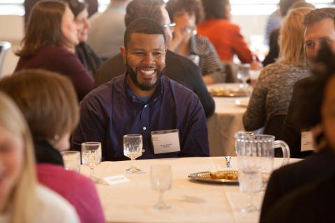 Man smiling while sitting at a meal table.