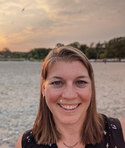 Woman smiling with a beach in the background.