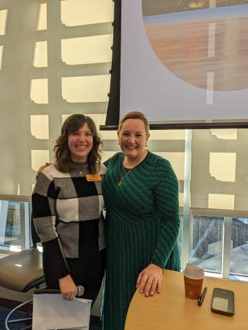 Two women standing next to each other smiling with their arms around each other's shoulders.