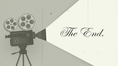 Gray image of an old projector shining a light on the words "The End."