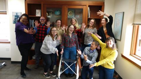 A group of smiling people throwing their hands up in celebration.