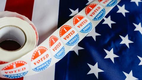A roll of stickers that read "I voted today" sit atop an American flag,