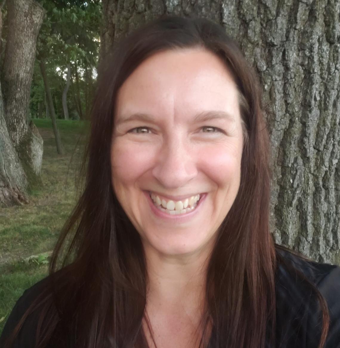 Woman smiling with long dark hair and wearing a black blouse.