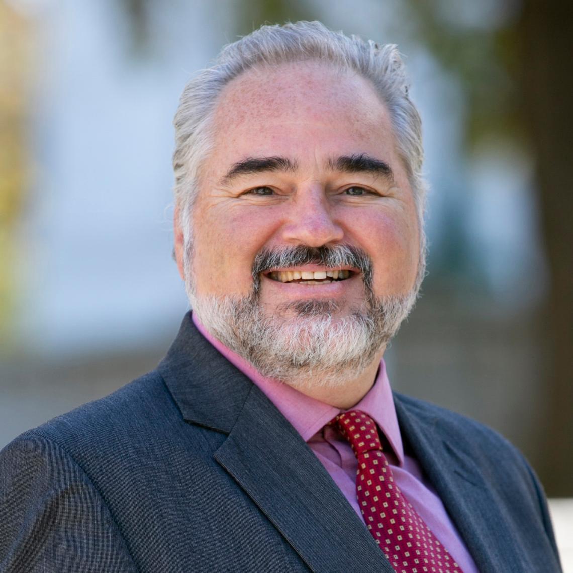 Man smiling wearing a suit and tie.