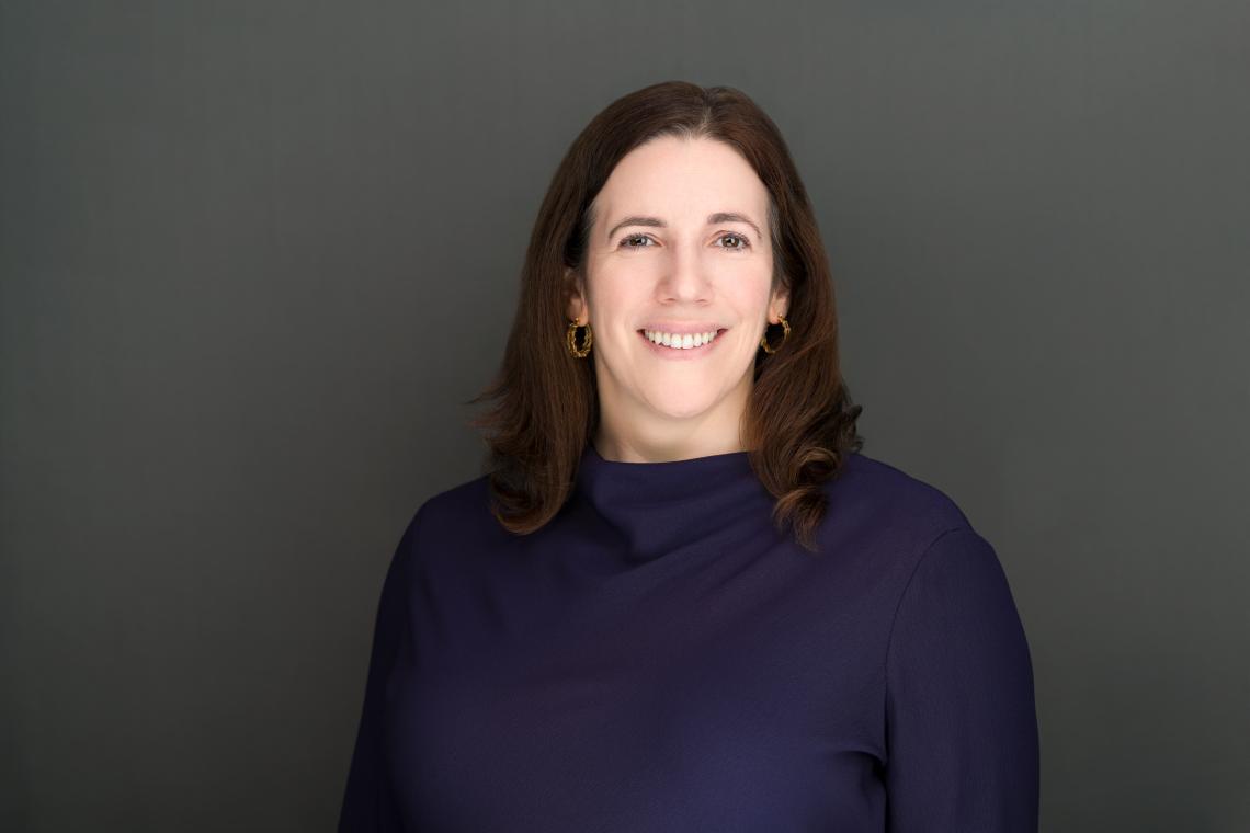 A dark gray background contains a woman wearing a dark blue sweater.